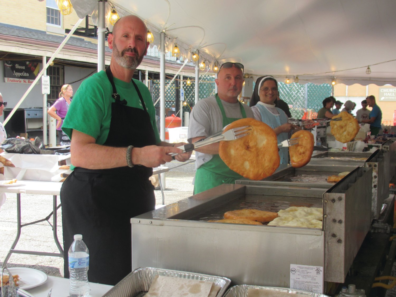 DELICIOUS DELIGHTS: Mike Carlino (left), his friend and Sister Daisy show of the freshly cooked doughboys countless people enjoy during the four-day feast and festival.